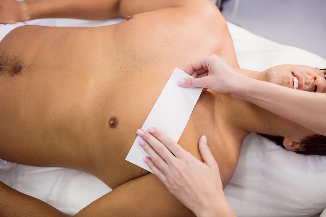 Man getting his chest waxed with wax strip at clinic